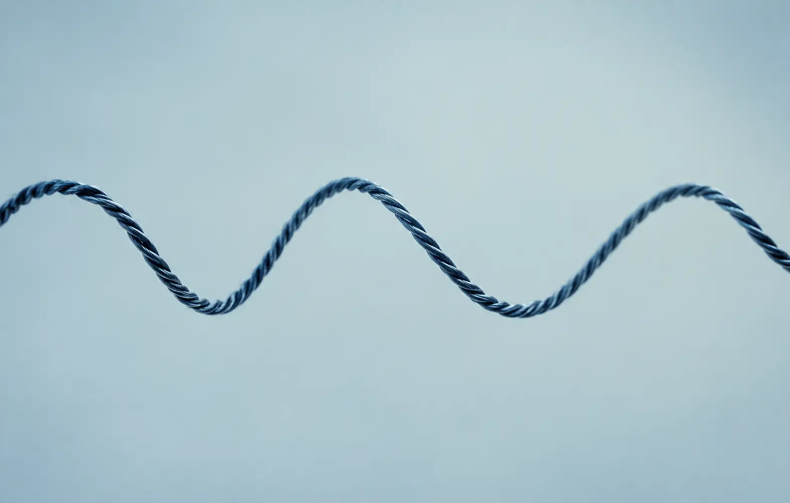 A coiled nitinol wire against a pale blue ground